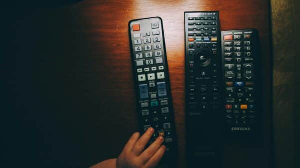 three black remote controls on wooden table