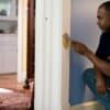 man in black crew neck t-shirt and blue denim jeans sitting on white wooden door