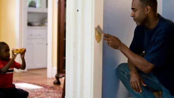 man in black crew neck t-shirt and blue denim jeans sitting on white wooden door