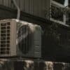 a white air conditioner sitting on top of a brick wall