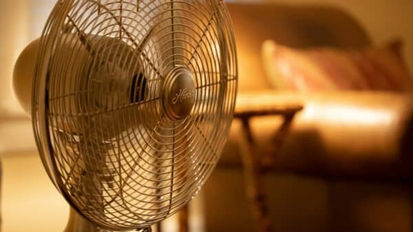 white stand fan turned on in room