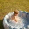 A child splashes in a small inflatable pool.