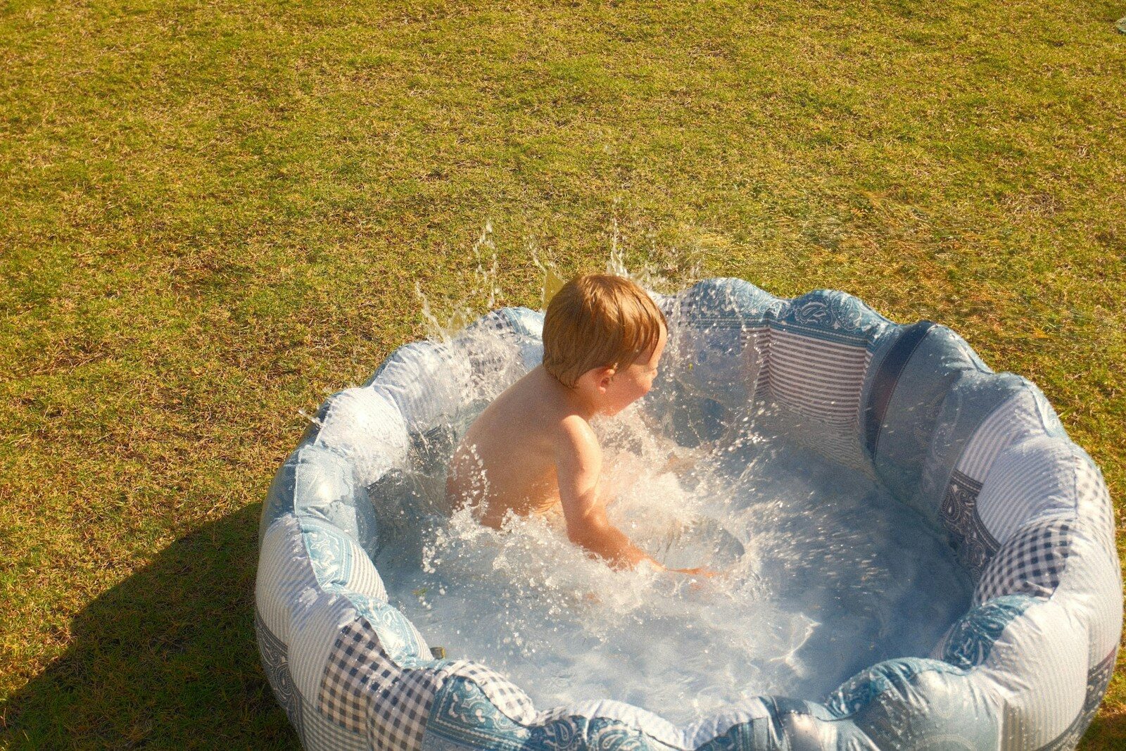 A child splashes in a small inflatable pool.