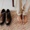 persons feet beside brown leather shoes
