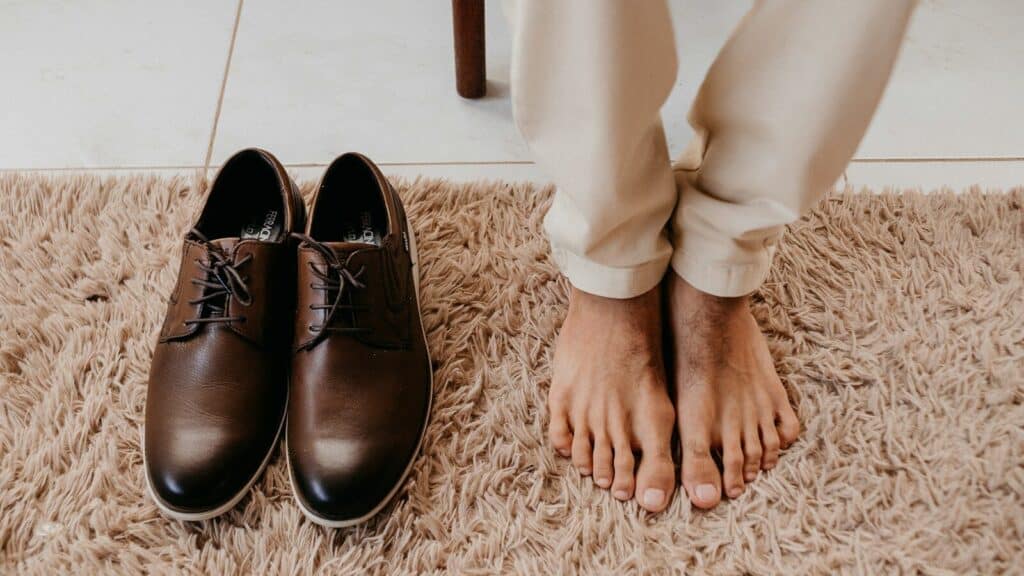persons feet beside brown leather shoes