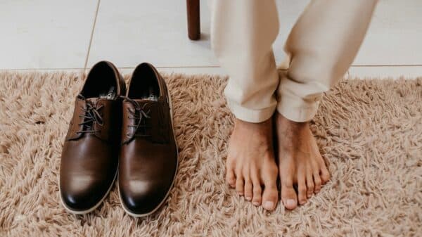 persons feet beside brown leather shoes