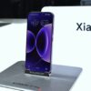 A purple xiaomi smartphone displayed on a stand.