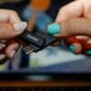 Two hands holding a sandisk usb flash drive.
