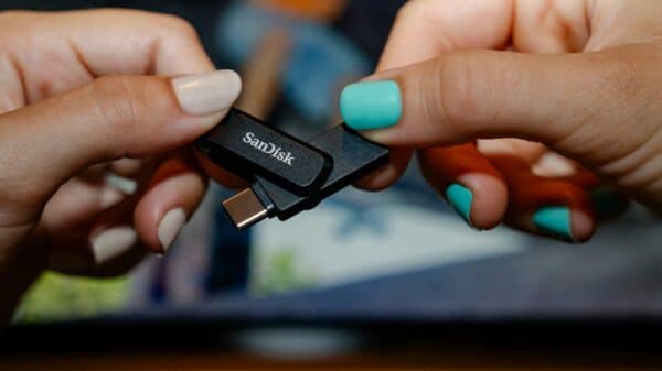 Two hands holding a sandisk usb flash drive.