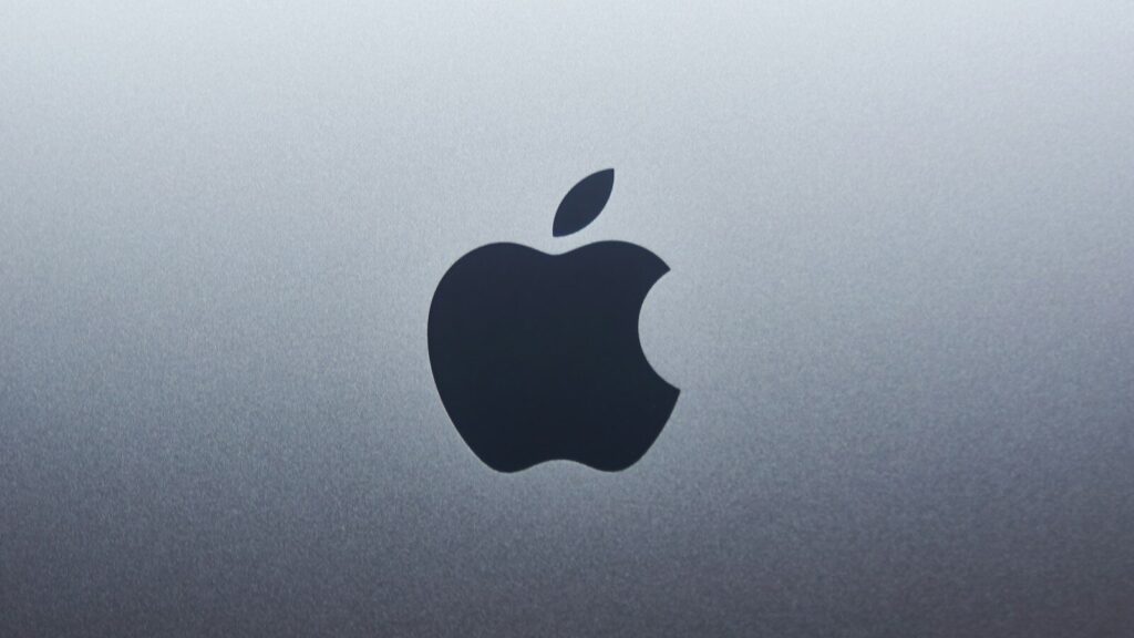A dark apple logo centered on a smooth grey metallic surface