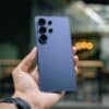 Hand holding a blue smartphone with multiple cameras