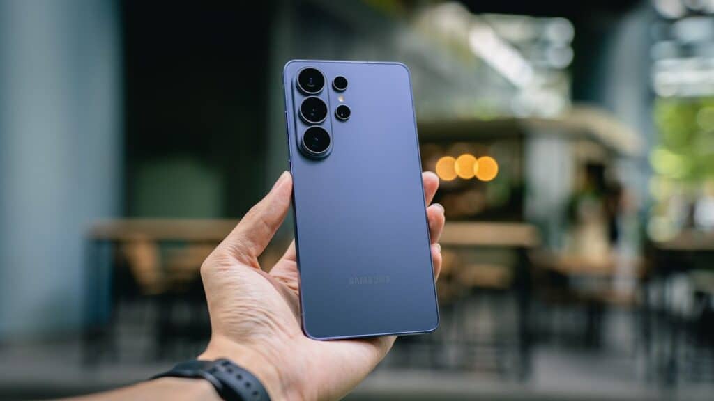 Hand holding a blue smartphone with multiple cameras