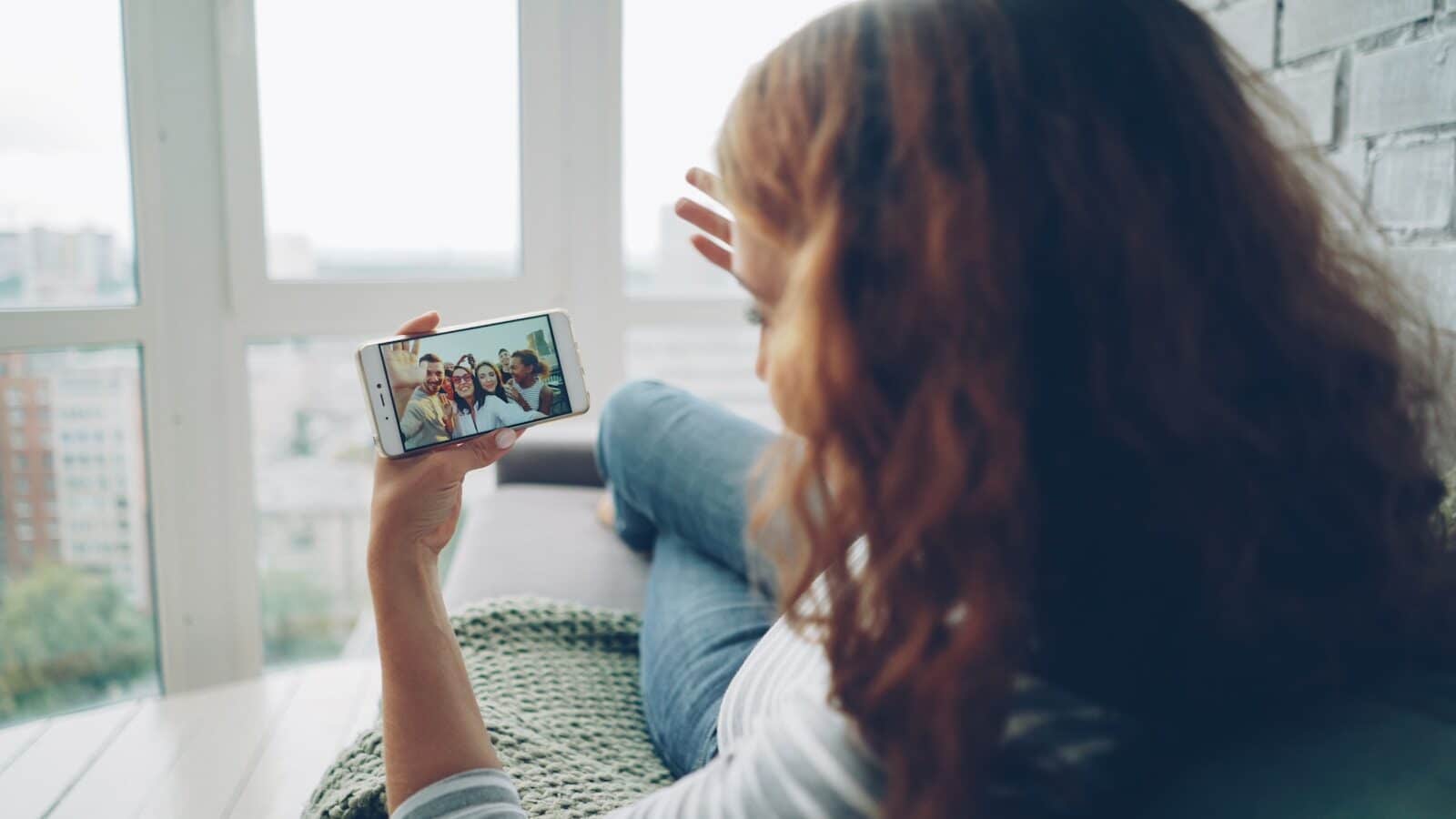 Woman watching video on smartphone by window