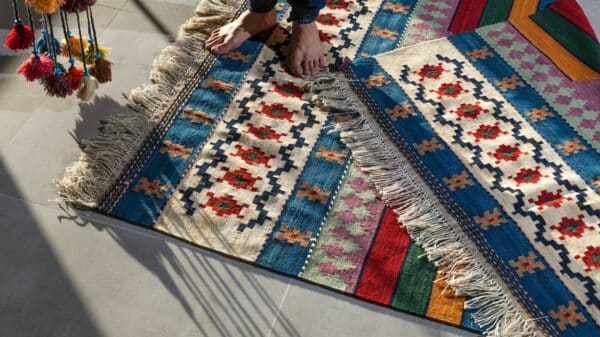 person in blue denim jeans standing on white blue and red area rug